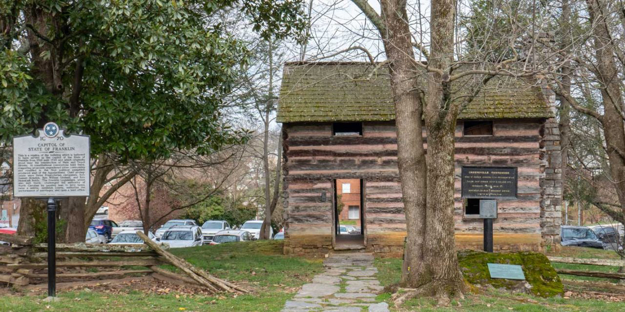 Historic site in downtown Greeneville with log home and history information signage